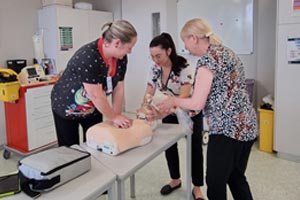 3 health professionals working with a training dummy