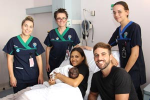 Three midwives surrounding the bed of a new baby and mother