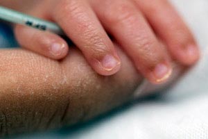 Tiny baby hand on adult finger