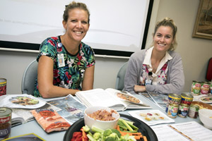 Two female health professionals sat with colourful vegetables