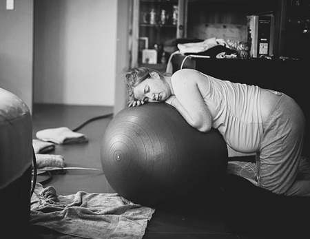 Woman in labour leaning over a birthing ball